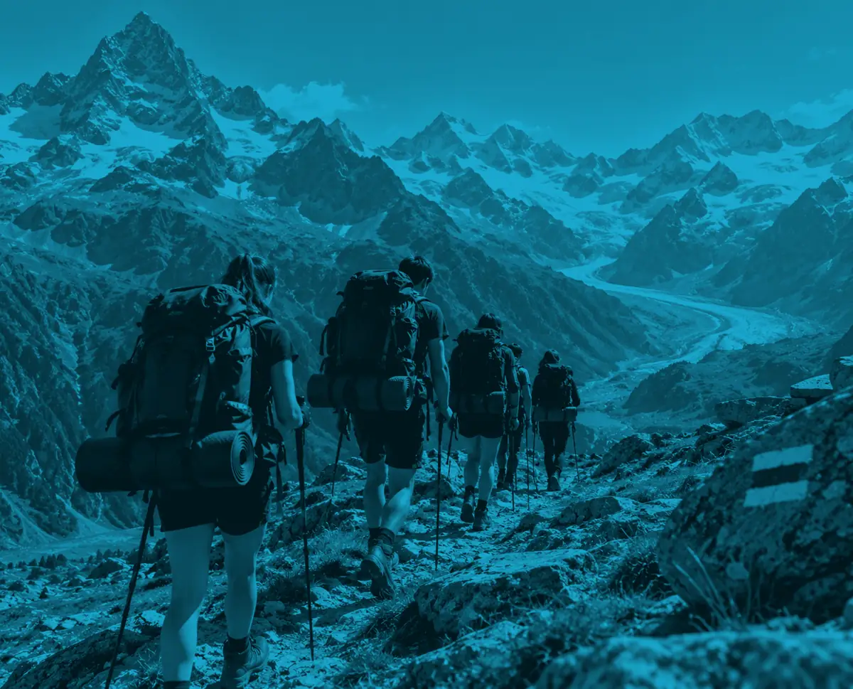 A Silver group walking in single file along an alpine path with snow peaks and a glacier ahead, washed in blue